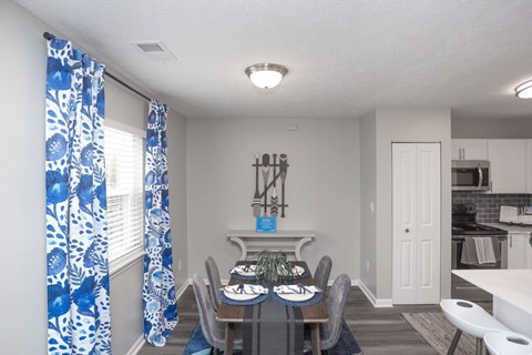 A dining room with a table set for two and a kitchen area in the background.