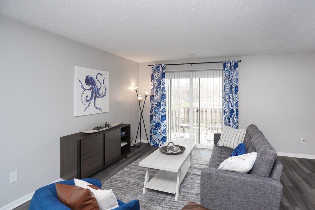 A living room with a grey couch, a white coffee table, and a blue ottoman.