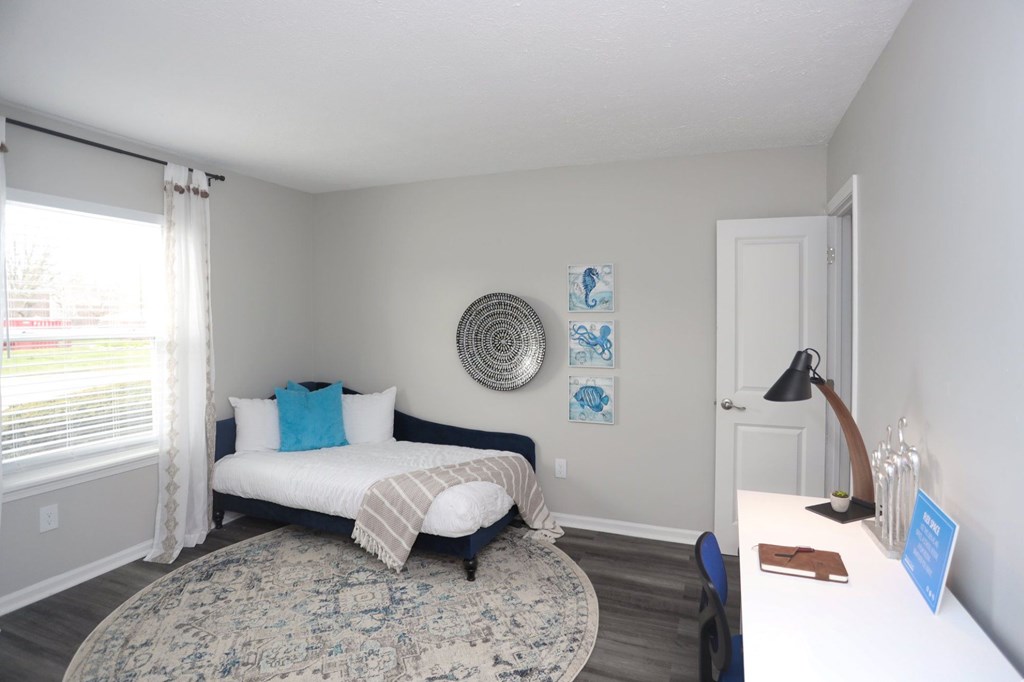A bedroom with a bed, a rug, a lamp, and pictures on the wall.
