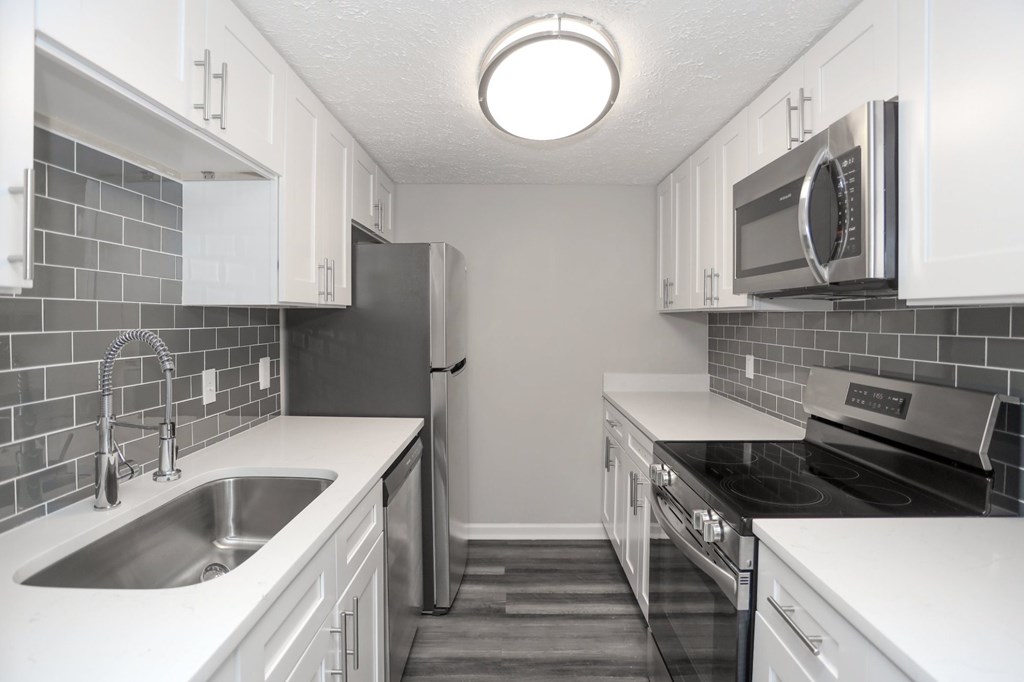 A kitchen with white cabinets and a black refrigerator.