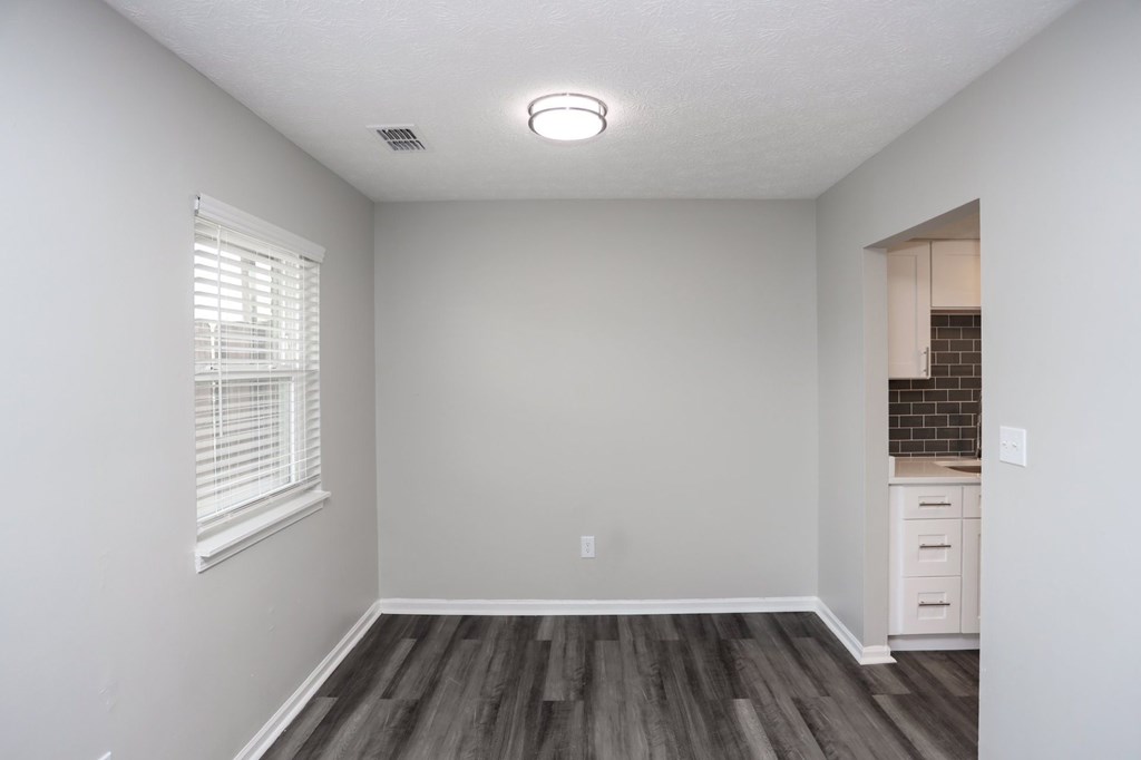 A room with a window and a wooden floor.