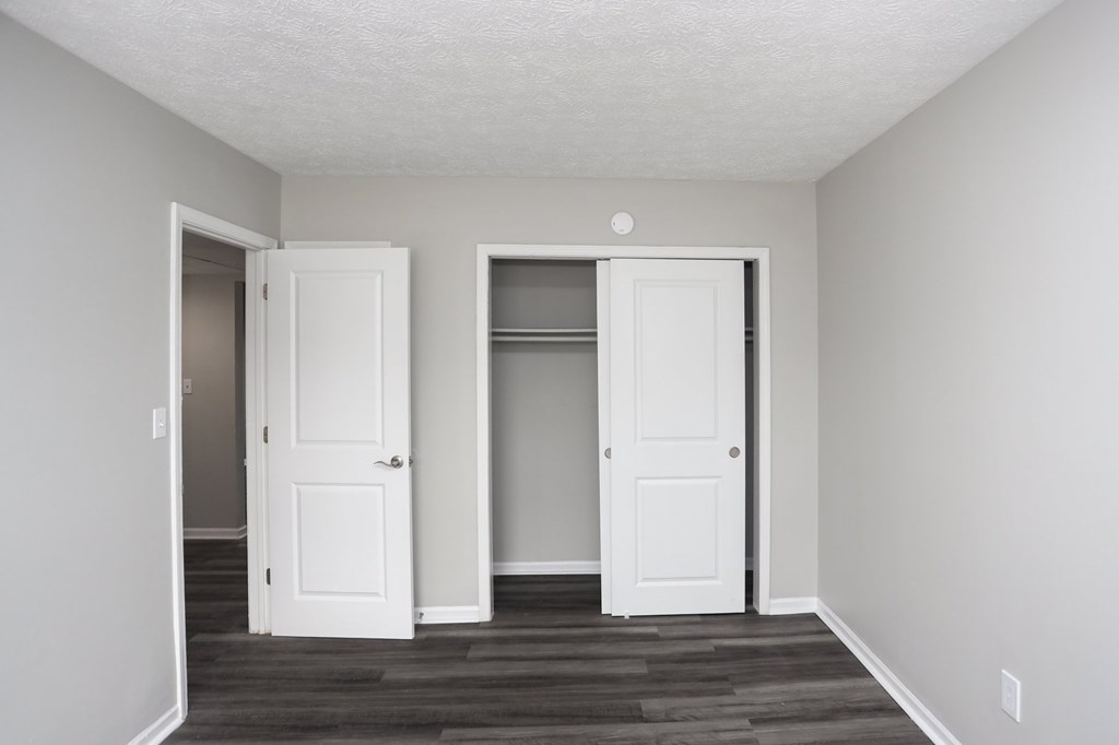 Two white doors in a room with wood flooring.