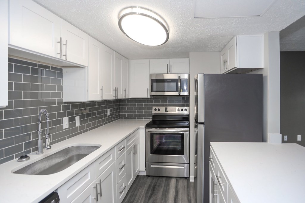 A modern kitchen with a stainless steel oven and white cabinets.