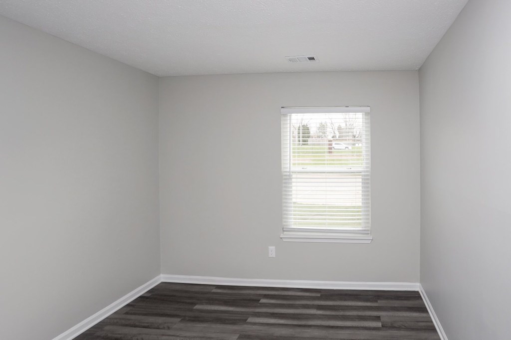 A room with a window and a wooden floor.