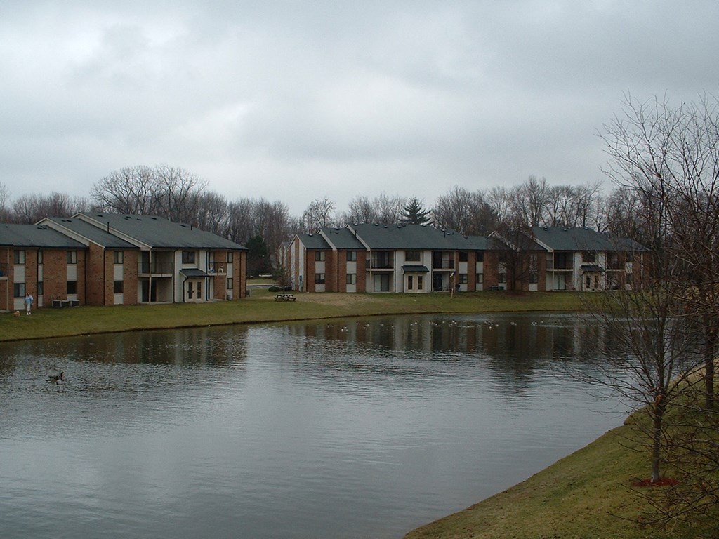 an apartment complex with a pond in front of it