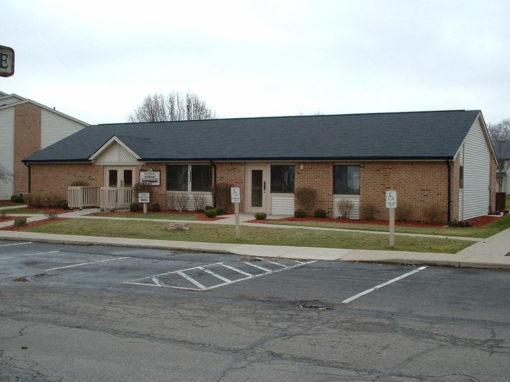 a small brick house with a porch and a parking lot