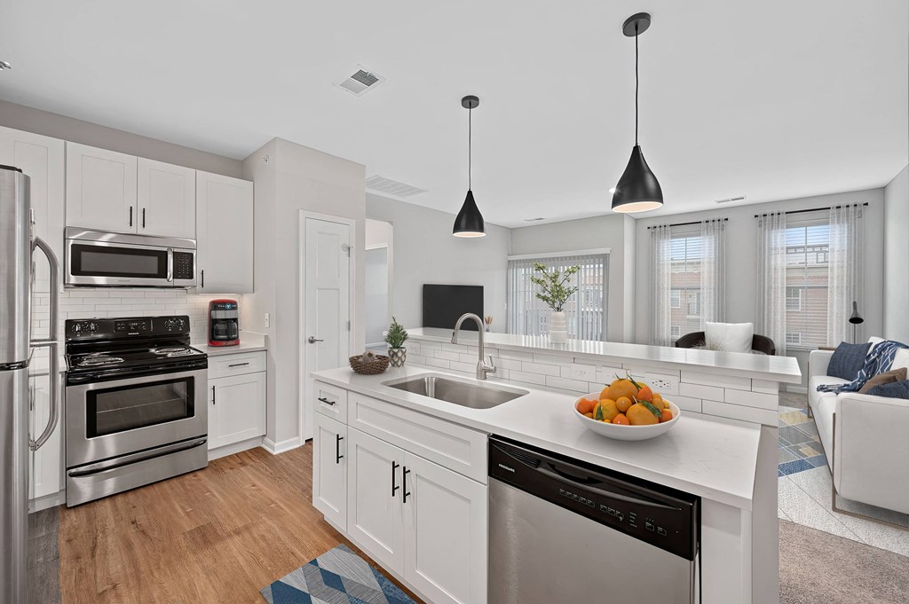 a white kitchen with a large counter top and a sink at Monmouth Row Apartments, Newport, KY, 41071