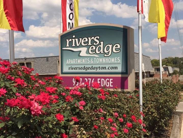 the sign for rivers edge apartments and townhomes with flowers