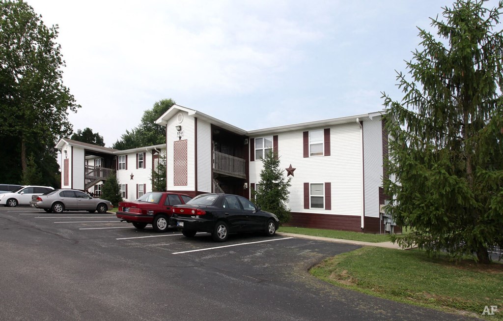 a parking lot with cars in front of a white and brown apartment complex at Ridgeview, Fortville, IN