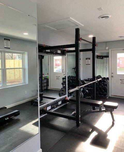 A gym with a squat rack and a bench.