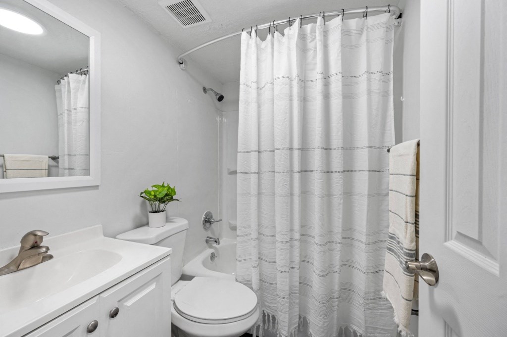 a bathroom with a white sink and toilet and a white shower curtain