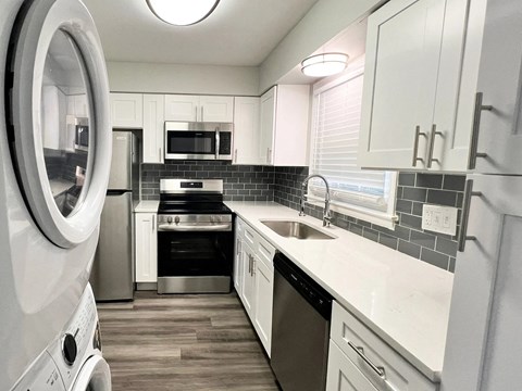 A modern kitchen with white cabinets and a black backsplash.