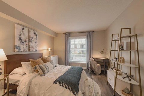 A bedroom with a large bed and a window with a view of the street at A62 Apartments, Indianapolis, IN 46220