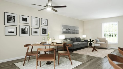 A living room with a grey couch, a wooden table and chairs, a rug, and a ceiling fan.