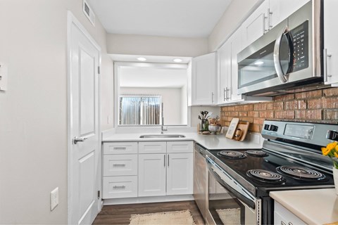 A kitchen with white cabinets and a brick backsplash at Fountain Parc Apartments, Indianapolis