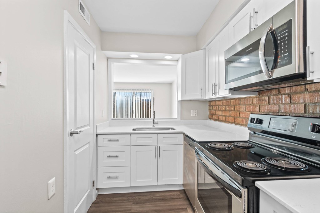 A kitchen with white cabinets and a brick backsplash at Fountain Parc Apartments, Indianapolis, Indiana