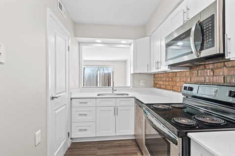 A kitchen with white cabinets and a brick backsplash at Fountain Parc Apartments, Indianapolis, Indiana