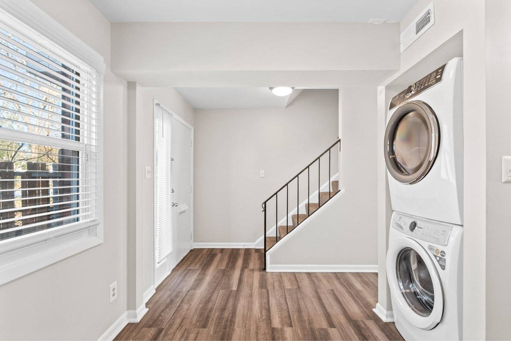 A white washing machine is in a laundry room with a staircase at Fountain Parc Apartments, Indianapolis, Indiana