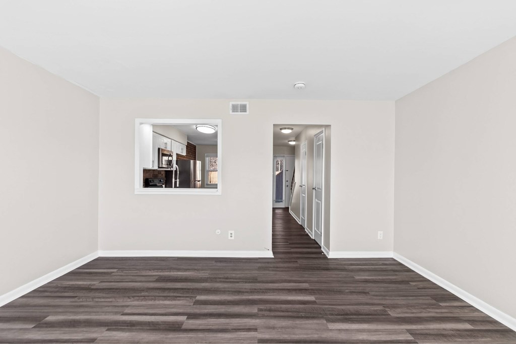 A long, empty hallway with a kitchen visible through the doorway at Fountain Parc Apartments, Indianapolis