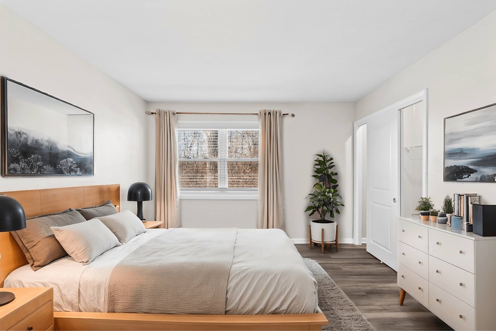 A bedroom with a large bed, a nightstand, and a dresser at Fountain Parc Apartments, Indianapolis, IN