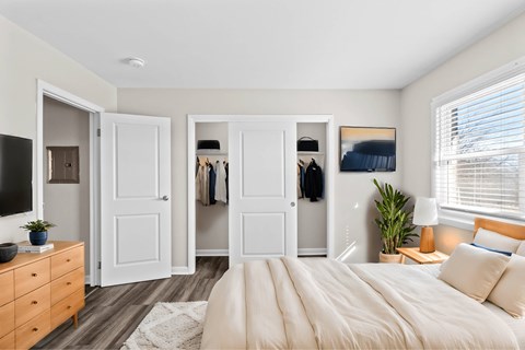A bedroom with a large bed, a dresser, and a mirror at Fountain Parc Apartments, Indianapolis, IN