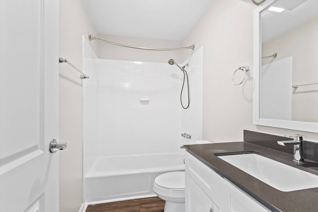 A white bathroom with a toilet, sink, and shower at Fountain Parc Apartments, Indianapolis, Indiana