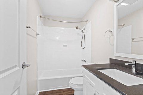 A white bathroom with a toilet, sink, and shower at Fountain Parc Apartments, Indianapolis, Indiana