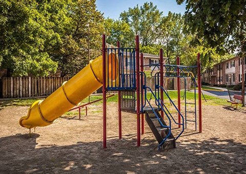 A playground with a yellow slide and a blue and red swing set at Fountain Parc Apartments, Indiana 46220