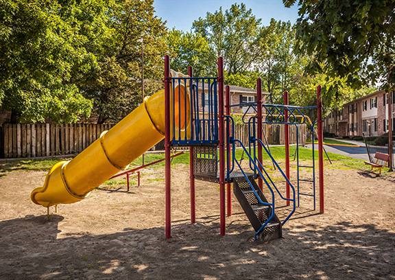 A playground with a yellow slide and a blue and red swing set A playground with a yellow slide and a blue and red swing set at Fountain Parc Apartments, Indiana 46220