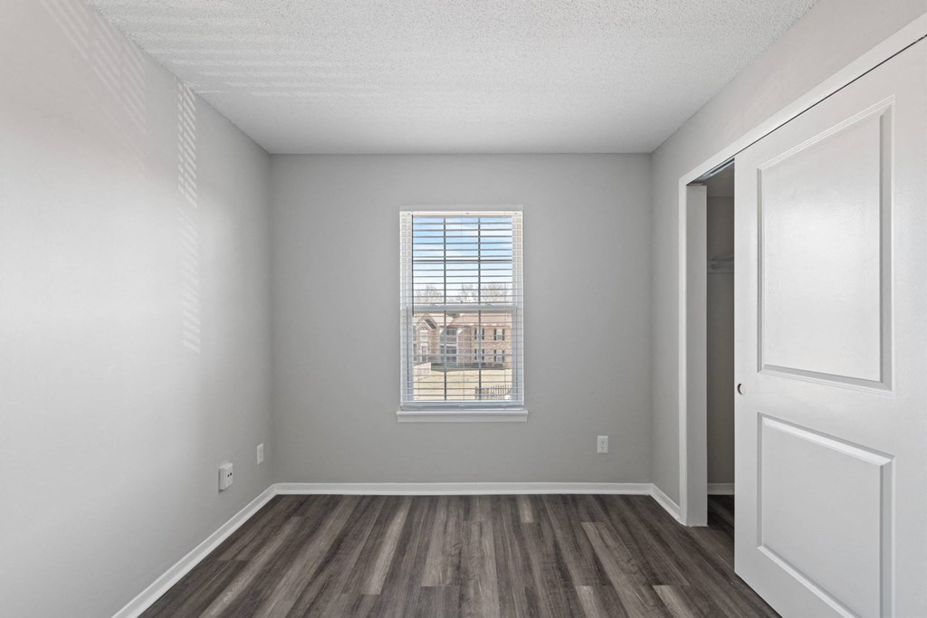 A room with a window showing a building outside.