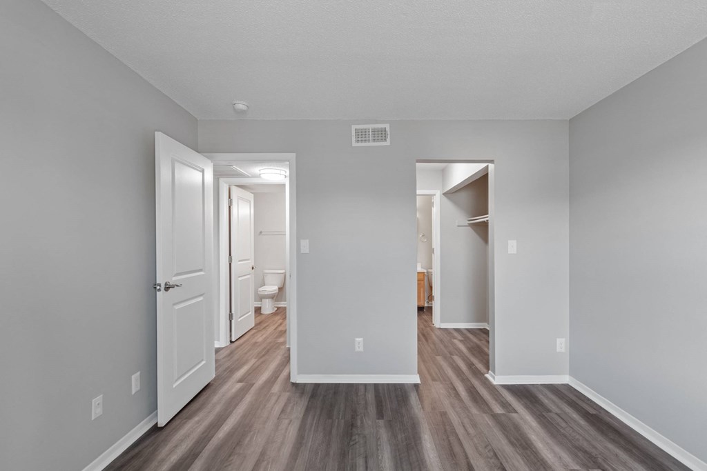 A long, narrow hallway with wood floors and white walls.