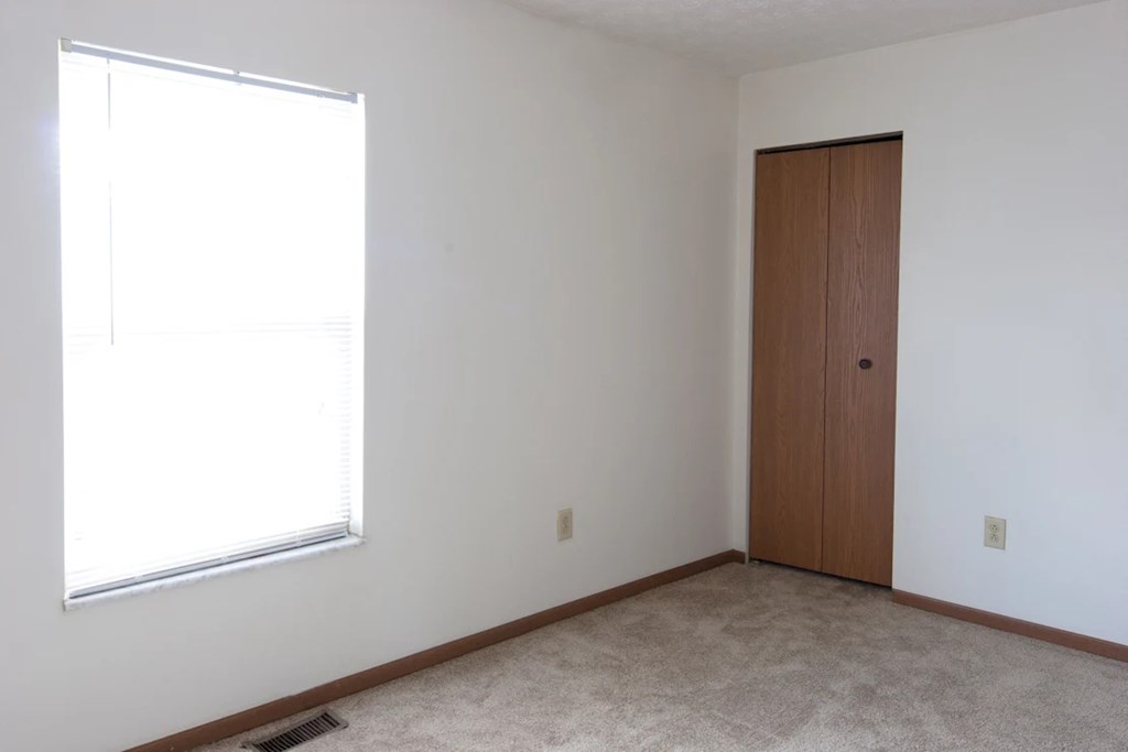 A room with a brown door and a window with blinds.