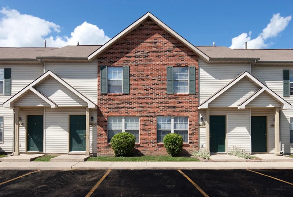 A brick house with a green door and a white garage door.