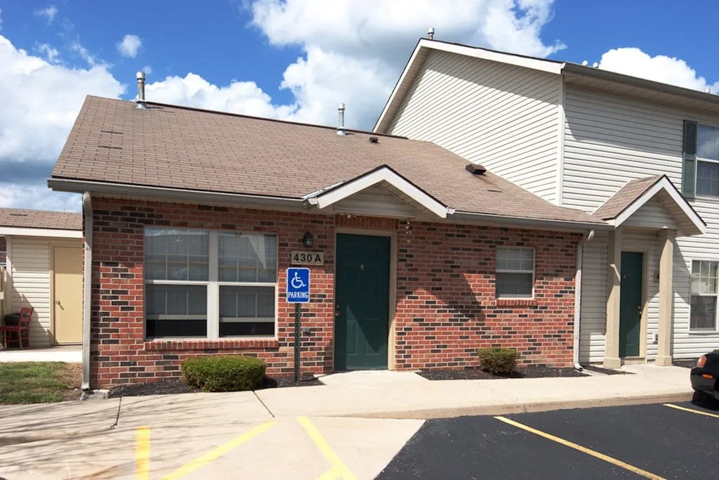 A small brick building with a green door and a handicap sign on the window.