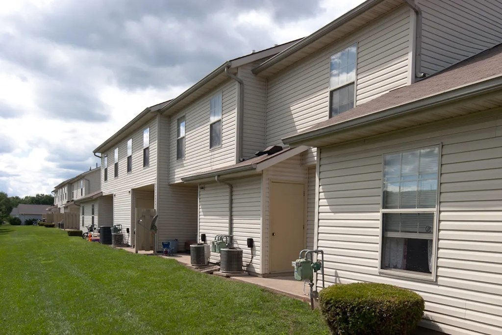A row of houses with green lawns and a cloudy sky.