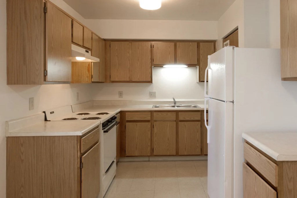 A kitchen with wooden cabinets and a white refrigerator.
