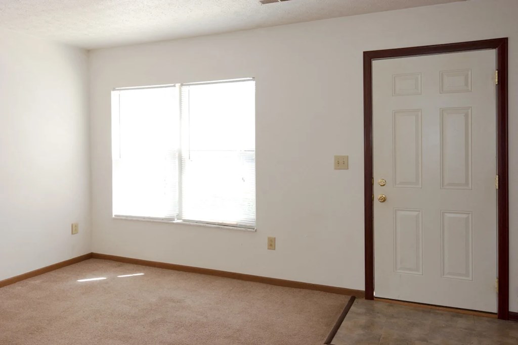 A room with a white door and a window with white blinds.