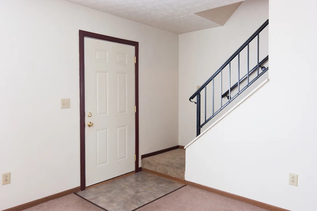 A white door with a brown frame is in a room with a carpeted floor.