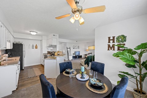 A dining room with a table set for four and a ceiling fan.