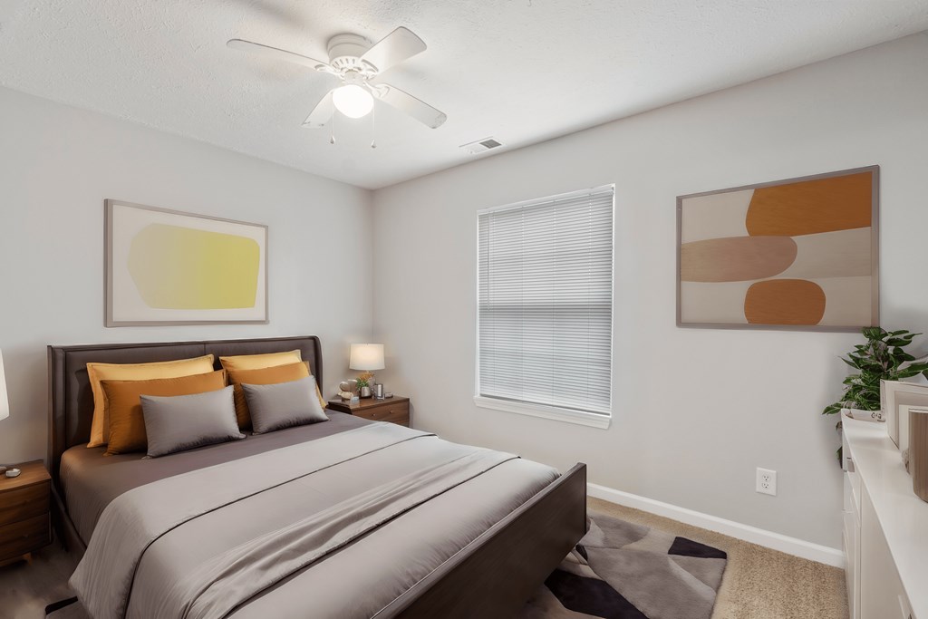 the model bedroom of an apartment with a bed and a ceiling fan