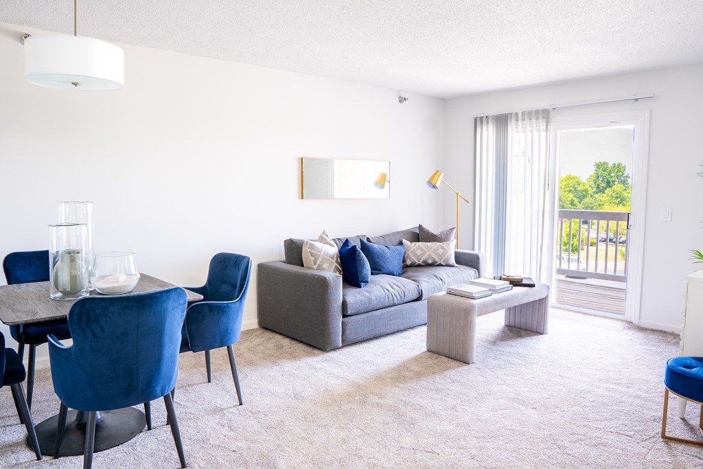 a living room with a couch table and chairs and a sliding glass door leading to a balcony
