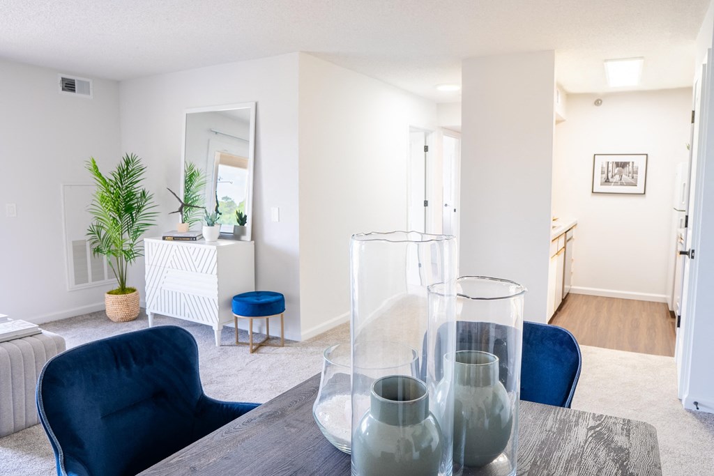 a living room with white walls and a wooden table with blue chairs