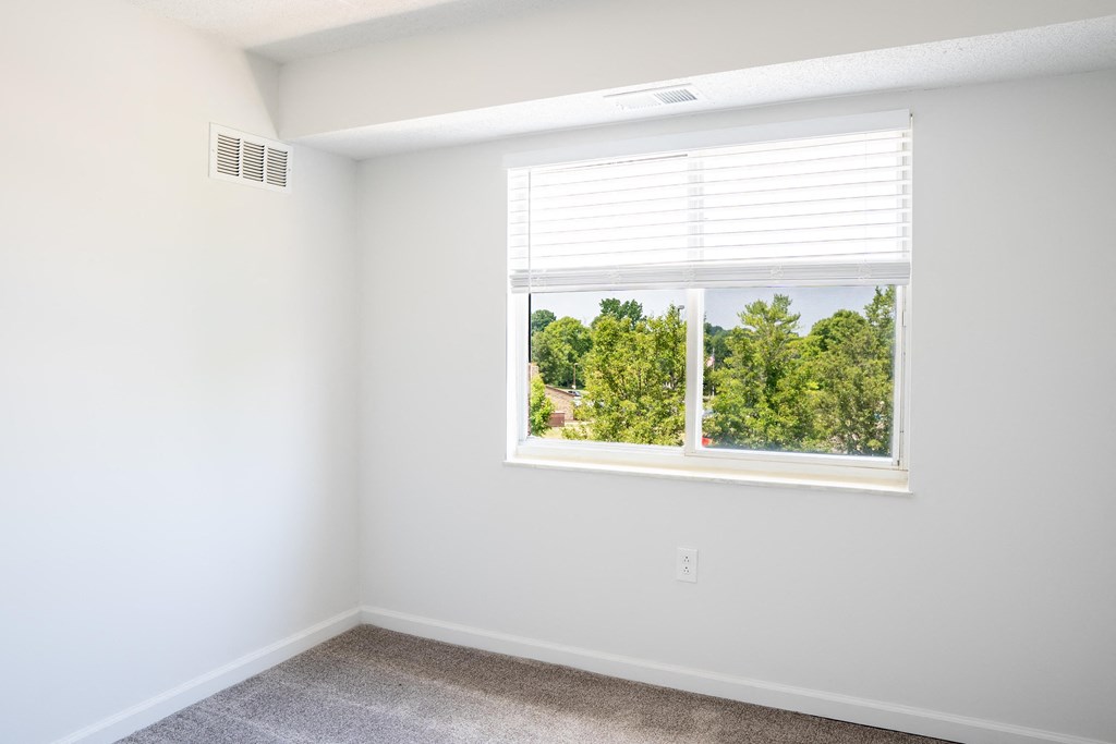 an empty room with a large window and a carpeted floor