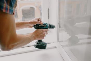 a man drilling into a window with a drill at Ivy Hills Living Spaces, Cincinnati