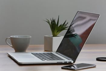 a laptop computer sitting on a desk next to a cup of coffee at Ivy Hills Living Spaces, Cincinnati