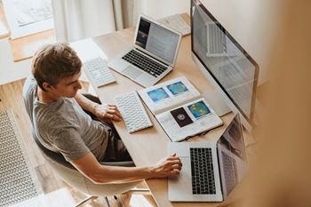 Man sitting at a desk with three laptops and a tablet  at Indian Lookout, Ohio, 45449