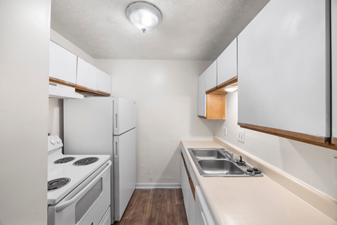 A small kitchen with white appliances and wood trim.