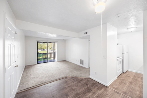 A spacious room with a window and sliding glass door.