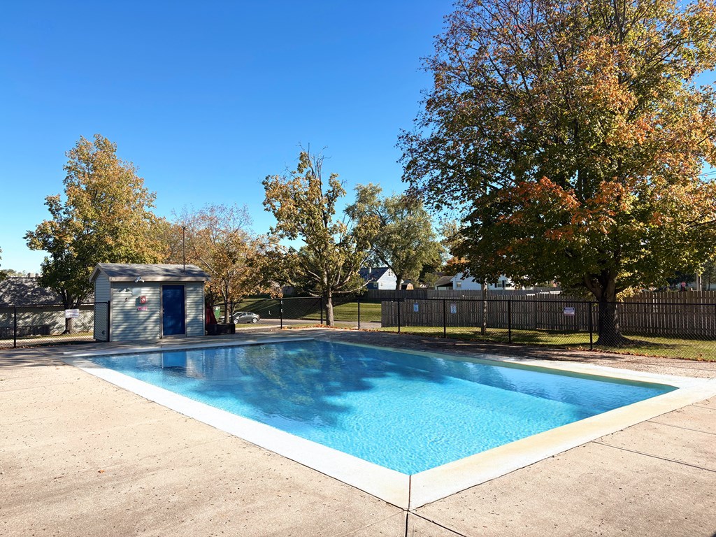 A small pool surrounded by a fence and trees.