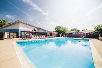 A large swimming pool with red chairs around it.